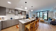 Located at 3275 Washington Blvd in Arlington, VA, this well-appointed two-bedroom, one-bathroom residence offers a thoughtfully designed open floor plan with modern finishes throughout. Light hardwood flooring runs seamlessly across the living spaces, enhancing the bright, airy atmosphere.

The kitchen is a standout feature, showcasing sleek grey cabinetry, marble-look tile backsplash, stainless steel appliances including a built-in oven and refrigerator, a ventilation hood, and under-cabinet lighting. A central island with a white quartz countertop provides additional prep space and casual seating with woven bar stools beneath globe pendant lights.

The living room is bathed in natural light from large, black-framed windows and sliding doors that open to a private balcony with outdoor views. The space offers a comfortable and versatile layout ideal for both relaxing and entertaining.

Both bedrooms are serene and well-proportioned, each featuring large windows with views of the surrounding neighborhood and ample closet storage. The primary bedroom provides a generous retreat with dedicated closet space.

The bathroom is finished with large-format dark tile surrounding a full soaking tub and shower combination. Two closets add practical storage throughout the residence, completing this well-designed urban home in the heart of Arlington.