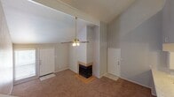 Located at 11240 Perry Rd in Houston, TX, this two-story home offers a thoughtfully arranged layout across two levels. The main living area makes a strong first impression with its vaulted ceilings, a ceiling fan, and a tile-surround fireplace as the room's focal point. Neutral carpet flooring extends throughout the living space, complemented by a bright, open feel enhanced by the elevated ceiling height.

The kitchen is well-equipped with white cabinetry, a marble-style countertop, and matching white appliances including an electric range, over-the-range microwave, and a full-size refrigerator. A peninsula provides additional counter space and casual seating potential. Light wood-look flooring ties the kitchen together with a clean, functional aesthetic.

Carpeted stairs lead to the upper floor, where the bedrooms are situated. Each bedroom features plush carpet flooring, a ceiling fan, and natural light from window openings fitted with blinds. The bathroom includes a single vanity with a large mirror, tile-surround bathtub and shower combination, and light wood-look flooring, maintaining a consistent, clean finish throughout the home. Overall, the space presents a practical and comfortable two-story layout suited for everyday living.