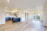 Located at 5127 Labounty Rd in Ferndale, Washington, this thoughtfully designed 3-bedroom, 2-bathroom residence offers a clean, modern aesthetic across a single level. The open-concept living and kitchen area serves as the heart of the home, featuring light-toned luxury vinyl plank flooring that extends throughout the main living spaces. Large windows flood the living room with natural light and frame views of the surrounding Pacific Northwest landscape, while sliding glass doors lead to a private balcony.

The kitchen is well-appointed with two-tone cabinetry — light upper cabinets paired with deep navy-blue lower cabinets — complemented by white countertops, a central island, pendant lighting, and a full suite of stainless steel appliances including a refrigerator, dishwasher, and microwave.

The three bedrooms are carpeted for comfort, each featuring sliding closet doors and ceiling-height walls that contribute to an airy feel. One bedroom includes a ceiling fan. The two bathrooms are finished in a clean, contemporary style — one with a soaking tub and shower combination, and the other with a glass-enclosed walk-in shower — both featuring wood-look flooring and sleek grey vanities with light countertops.