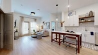 Located at 1200 Marquis Pkwy in Williamsburg, VA, this well-appointed residence offers four bedrooms and two full bathrooms across a single floor. The open-concept layout connects the kitchen and living area seamlessly, creating an inviting, communal atmosphere filled with natural light from large windows dressed in sheer linen curtains.

The kitchen is outfitted with white shaker-style cabinetry, stainless steel appliances, a tile backsplash, open wood shelving, and a quartz countertop island with pendant lighting — ideal for both cooking and casual dining. The living room features light wood-style flooring, generous wall space, and access to a private exterior door.

The four bedrooms are carpeted for comfort and each benefits from natural light through sizable windows. The primary bedroom is a well-proportioned retreat, while the additional bedrooms offer flexibility for various living arrangements.

The two bathrooms are finished in a clean, contemporary style. One features a walk-in glass shower and white cabinetry with matte black hardware, while the second includes a tub-shower combination — both with light wood-style flooring and white vanities.

Throughout the residence, a neutral color palette, modern fixtures, and consistent finishes create a cohesive and functional living environment.