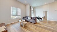 Located at 748 Irolo St in Los Angeles' Koreatown neighborhood, this 3-bedroom, 2-bathroom unit is thoughtfully designed across a single floor. The open-concept living and kitchen area serves as the heart of the unit, where soaring ceilings amplify the sense of space. Large windows flood the living room with natural light and offer views of the surrounding cityscape, complementing the warm, light-toned hardwood-style flooring found throughout.

The kitchen is a standout feature, equipped with gray shaker cabinetry, stainless steel appliances including a gas range and French door refrigerator, a wall-mounted range hood, and a generous quartz island with an undermount sink—ideal for both cooking and casual dining.

The primary bedroom is a comfortable retreat with a dedicated walk-in closet outfitted with multi-level shelving and hanging rods. The two bathrooms are finished in a clean, contemporary style; the primary bath features a dual-sink vanity with backlit mirror and a tub-shower combination, while the secondary bath includes a tub-shower and a window for natural ventilation. A hallway connects the private sleeping quarters, maintaining a clear separation between the living and bedroom areas.