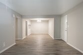 This single-story, 3-bedroom, 2-bathroom home offers a practical and comfortable layout across a well-utilized floor plan. The living room is bright and open, featuring light-toned hardwood-style flooring, neutral walls, and a textured ceiling. A set of French doors floods the space with natural light and provides outdoor access, creating a welcoming atmosphere. Adjacent to the living area, the dining room is defined by a stylish multi-bulb chandelier and a pass-through window connecting to the kitchen, enhancing the open flow between spaces.

The kitchen is well-appointed with white cabinetry, light quartz-style countertops, a stainless steel sink, and black appliances including an electric range and dishwasher. Hardwood-style flooring continues throughout, giving the kitchen a clean, cohesive look.

The three bedrooms are carpeted for comfort, each with neutral walls and textured ceilings. The primary bedroom includes a walk-in closet outfitted with dual shelving rods and built-in shelves, offering generous storage. The remaining bedrooms are versatile in size and well-suited for various uses.

The two bathrooms feature tile flooring and white vanities with light countertops. Two hallways connect the living areas to the private quarters, with three closets distributed throughout the home for ample storage.