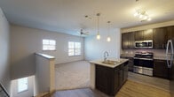 Located in Forney, Texas, this single-story residence offers a well-designed open-concept layout that seamlessly connects the kitchen and living areas. The kitchen is a standout feature, equipped with dark espresso cabinetry, granite countertops, a tile backsplash, and a full suite of stainless steel appliances including a refrigerator, range, and microwave. A central island with a built-in sink and pendant lighting above serves as both a functional workspace and a natural gathering point. Track lighting further illuminates the kitchen, while wood-style flooring grounds the space with warmth and durability. The adjacent living area transitions to plush carpet and is fitted with a ceiling fan, with windows providing natural light throughout. A low half-wall with a finished ledge defines the boundary between the living space and the entry hallway, adding architectural character. The bathroom features a full soaking tub and shower combination with white tile surround and chrome fixtures. Bedrooms are carpeted and offer generous proportions, with at least one room featuring a walk-in closet outfitted with wire shelving and hanging rods for organized storage. The overall design is clean, functional, and well-suited for comfortable everyday living.