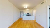 Located along Biscayne Boulevard in North Miami, this single-floor unit presents a clean, modern design with a cohesive aesthetic carried throughout every room. The open-concept living and kitchen area serves as the heart of the space, where warm-toned hardwood flooring extends seamlessly underfoot, complementing the bright white walls and creating an inviting, airy atmosphere. Overhead, globe-cluster light fixtures add a contemporary accent to the layout.

The kitchen is anchored by a sleek peninsula with a dark countertop, providing both workspace and a natural divider between the living area and cooking zone. White upper cabinetry, a subway tile backsplash, a gold-toned faucet, and stainless steel appliances — including a refrigerator, microwave, and range — contribute to the kitchen's polished, functional character.

The bedrooms maintain the same hardwood flooring and crisp white walls, with at least one room featuring a large window that frames views of the surrounding tropical greenery, allowing generous natural light to filter in.

The bathroom offers a refined finish with dark granite countertops, dual undermount sinks, wood-toned cabinetry, large-format tiled walls surrounding the soaking tub and shower, and a full-width mirror that enhances the sense of space. A louvered closet door adds a classic detail to the room's overall modern composition.