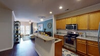 This single-floor residence at 3050 Plantation Garden Way in Fayetteville, NC, offers a thoughtfully designed layout with modern finishes and a warm, cohesive aesthetic throughout. The open-concept kitchen is a standout feature, equipped with rich honey-toned wood cabinetry, granite countertops, a classic subway tile backsplash, stainless steel appliances, and a center island with bar seating — ideal for both everyday cooking and entertaining. The kitchen flows seamlessly into the combined living and dining area, which is anchored by a bold teal accent wall, crown molding, recessed lighting, and hardwood-style flooring. French doors in the living room invite natural light and provide outdoor access. The primary bedroom is a comfortable retreat featuring plush carpeting and a ceiling fan, with direct access to an en-suite bathroom. Additional bedrooms offer ample natural light through large windows and generous closet space. The bathrooms are finished with granite-topped vanities, warm wood cabinetry, and tub-shower combinations. Throughout the residence, consistent design details — including crown molding, neutral tones, and durable hardwood-style flooring in the main areas — create a cohesive and inviting living environment.
