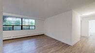 This 2-bedroom, 1-bathroom unit at 1320 Danforth Road offers a clean, modern interior with a cohesive design throughout. Light wood laminate flooring runs continuously across all rooms, lending a bright and airy feel to the entire space. The living room is generously proportioned, anchored by a wide bank of floor-to-ceiling windows fitted with baseboard heating beneath, allowing natural light to pour in while framing views of the surrounding greenery and neighbourhood streetscape. The kitchen is well-equipped with white shaker-style cabinetry, dark countertops, a classic white subway tile backsplash, and stainless steel appliances including a refrigerator and dishwasher. Both bedrooms are comfortably sized, each featuring sliding panel closets and large windows with baseboard heaters. The primary bedroom offers a dedicated closet and a calm, neutral atmosphere. The bathroom is finished in crisp white subway tile, complete with a soaker tub and shower combo, a white vanity with an undermount sink, and chrome fixtures. Throughout the unit, white walls and clean trim work contribute to a fresh, move-in-ready aesthetic that is both functional and inviting.