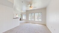 Located in Peoria, Arizona, this 2-bedroom, 1-bathroom residence offers a well-organized single-floor layout designed for comfortable everyday living. The open-concept living room is bright and airy, featuring large windows with vertical blinds that invite an abundance of natural light, soft carpeting underfoot, and a ceiling fan with light fixture overhead. The space flows seamlessly into the kitchen, which is equipped with light wood cabinetry, dark countertops, a full suite of white appliances including an electric range, microwave, and dishwasher, and wood-look flooring that extends throughout the kitchen and bathroom areas. A raised breakfast bar separates the kitchen from the living area, adding a functional and social element to the layout. The primary bedroom is generously sized, complete with a ceiling fan, sliding glass door leading to an outdoor patio, and access to a large walk-in closet outfitted with dual-level shelving rods. The second bedroom is a comfortable, carpeted room with ample natural light from a side window and its own ceiling fan. The bathroom features wood-look flooring, a wide vanity with dark countertops, white cabinetry, and a well-lit mirror. The overall aesthetic is clean and neutral throughout.