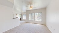 Located in Peoria, Arizona, this 2-bedroom, 1-bathroom residence offers a well-organized single-floor layout designed for comfortable everyday living. The open-concept living room is bright and airy, featuring large windows with vertical blinds that invite an abundance of natural light, soft carpeting underfoot, and a ceiling fan with light fixture overhead. The space flows seamlessly into the kitchen, which is equipped with light wood cabinetry, dark countertops, a full suite of white appliances including an electric range, microwave, and dishwasher, and wood-look flooring that extends throughout the kitchen and bathroom areas. A raised breakfast bar separates the kitchen from the living area, adding a functional and social element to the layout. The primary bedroom is generously sized, complete with a ceiling fan, sliding glass door leading to an outdoor patio, and access to a large walk-in closet outfitted with dual-level shelving rods. The second bedroom is a comfortable, carpeted room with ample natural light from a side window and its own ceiling fan. The bathroom features wood-look flooring, a wide vanity with dark countertops, white cabinetry, and a well-lit mirror. The overall aesthetic is clean and neutral throughout.