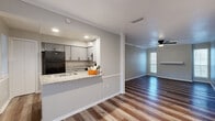 Located at 13980 Peyton Drive in Dallas, TX, this 2-bedroom, 4-bathroom single-floor unit offers a practical and modern layout designed for comfortable living. The open living and dining area features wood-look plank flooring, neutral gray walls, crown molding, and a ceiling fan, creating a bright and welcoming atmosphere. Natural light filters in through a window at the far end, adding warmth to the space. The kitchen is efficiently designed with gray shaker-style cabinetry, granite countertops, black appliances including a refrigerator and range, a peninsula with a sink, and recessed lighting — all flowing seamlessly into the main living area. A dedicated pantry and in-unit laundry room add practical convenience. Both bedrooms are carpeted and include ceiling fans; the primary bedroom offers generous closet space with multiple storage options, including a walk-in-style closet with shelving. The four bathrooms are well-appointed, featuring granite-topped vanities with gray cabinetry and black hardware, with at least one bathroom showcasing a tiled walk-in shower. A hallway connects the private areas of the unit, and four closets throughout provide ample storage. The overall aesthetic is clean and contemporary with consistent finishes across the space.