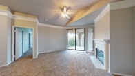 This single-floor residence offers a thoughtfully designed layout with a variety of functional and comfortable spaces throughout. The living room serves as the centerpiece of the home, featuring vaulted ceilings with a ceiling fan, a classic white-mantled fireplace with tiled surround, and a large sliding glass door that opens to a private balcony, filling the room with natural light and outdoor views. Plush carpeting extends throughout the living areas and bedrooms, adding warmth to the neutral, softly painted interiors.

The kitchen is well-equipped with stainless steel appliances, including a range and over-the-range microwave, ample white cabinetry, light stone-look countertops, and wood-look vinyl plank flooring that extends into the dining and entry areas. A pass-through counter connects the kitchen to the main living space.

The bedrooms offer generous proportions, with one featuring built-in shelving, an arched window, a walk-in closet, and a ceiling fan. Additional bedrooms are bright and carpeted, with multiple windows allowing natural light. Two full bathrooms are finished with wood-look plank flooring, vanities with storage, and clean white fixtures — one with a tub/shower combo. The textured ceilings and crown molding details add a classic finishing touch throughout.