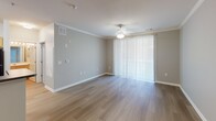 Located at 105 Kings Farm Road in Rockville, MD, this single-floor residence offers a well-designed, open-concept layout that balances comfort and functionality. The living area features light hardwood-style flooring, crown molding, a ceiling fan, and a large sliding glass door dressed with vertical blinds that floods the space with natural light. Track lighting along the ceiling adds a modern touch to the open layout.

The kitchen flows seamlessly from the living area and is appointed with warm honey-toned wood cabinetry, dark granite-style countertops, and a full suite of black appliances including a gas range, over-the-range microwave, and refrigerator. A peninsula counter provides both additional prep space and a natural divide between the kitchen and living areas.

The bedrooms are carpeted in neutral tones and feature large windows that offer views of the surrounding greenery, filling each room with ample natural light. Closet access is conveniently located within or adjacent to each bedroom. The bathroom is well-appointed with a tiled shower-tub combination, a curved curtain rod, wood-look flooring, and a vanity with a light countertop. Neutral gray walls throughout the unit create a cohesive, modern aesthetic.