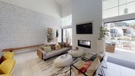 Located at 309 Solana Hills Dr in Solana Beach, California, this two-floor space delivers a sophisticated blend of modern design and functional versatility. The main living area immediately impresses with soaring double-height ceilings, a bold textured accent wall, and a sleek linear fireplace framed in crisp white paneling. Large-format tile flooring, vibrant eclectic furnishings, and abundant natural light filtering through expansive clerestory windows create an energetic yet welcoming ambiance. A dedicated game room features light hardwood-style flooring, a full-size pool table with a rustic wood base, and a casual dining set tucked into a naturally lit corner — ideal for recreation and social gatherings. The kitchenette is well-appointed with light wood cabinetry, a stone mosaic tile backsplash, stainless steel under-counter refrigeration, and dual counter stations with windows overlooking the exterior. A cozy lounge nook offers leather seating, a geometric-patterned area rug, and curated décor for a more intimate retreat. Exposed industrial ductwork adds an architectural contrast to the otherwise clean, white interior palette. Throughout both floors, the design emphasizes open, multi-functional spaces filled with natural light and thoughtful finishing details.