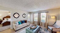 Located at 6201 Windhaven Pkwy, this single-floor residence offers a thoughtfully designed layout with a cohesive, contemporary aesthetic throughout. The living area serves as the heart of the home, featuring light wood-style flooring, a textured ceiling, and multiple windows dressed with elegant curtain panels that invite an abundance of natural light. The space is generously sized to accommodate both a full sofa arrangement and additional seating, creating a versatile and welcoming environment. Decorative quatrefoil mirrors accent the neutral-toned walls, adding a stylish focal point to the room.

The kitchen is efficiently laid out with white cabinetry, granite countertops, stainless steel appliances including a dishwasher and refrigerator, and recessed lighting that keeps the workspace bright and functional. Light wood-style flooring continues seamlessly from the living area into the kitchen.

The bedroom is a serene retreat featuring plush carpeting, a ceiling fan with light fixture, and a window that allows soft natural light to filter in. A walk-in closet provides ample storage space. The bathroom complements the home's refined aesthetic with white cabinetry, granite countertops, a large vanity mirror, and brushed nickel fixtures, completing this well-appointed residence.