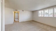 Located along E Harvard Ave in Denver, Colorado, this single-floor unit offers three bedrooms, one bathroom, a kitchen, and a hallway within a well-organized and efficient layout. The bedrooms feature neutral-toned carpet flooring, white walls, and textured ceilings. Each room is filled with natural light through blinded windows, and the generously sized primary bedroom stands out with dual windows that brighten the space considerably. The secondary bedrooms are cozy and functional, each with wood-toned doors. One bedroom includes a double sliding closet for added storage. The galley-style kitchen is outfitted with white cabinetry, light countertops, a coil-burner electric range, a dishwasher, and a stainless steel sink, all set over wood-look vinyl flooring. The full bathroom features a tiled tub-shower combo, a white vanity with a single sink, and matching wood-look flooring. The entry area transitions from hard flooring to carpet and includes a ceiling fan and a closet. Throughout the unit, the clean, neutral palette and consistent finishes create a bright, move-in-ready atmosphere.