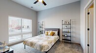 This well-designed one-bedroom, two-bathroom residence in Cleveland's 44113 zip code offers a thoughtfully planned single-floor layout with modern finishes throughout. The open-concept kitchen is a standout feature, showcasing sleek gray cabinetry, a white subway tile backsplash, stainless steel appliances, light hardwood-style flooring, and a striking stone-topped island with pendant lighting overhead — ideal for both meal prep and casual dining. The living room maintains the same light flooring and benefits from generous natural light through large windows, creating a bright and welcoming atmosphere with notable ceiling height. The spacious primary bedroom features plush carpeting, a ceiling fan, large windows that invite abundant natural light, and access to two closets — one of which is a walk-in equipped with wire shelving systems for ample storage. Both bathrooms carry the contemporary aesthetic forward, with gray vanities, white countertops, black hardware accents, and light wood-style flooring. Throughout the space, a consistent neutral gray palette paired with black hardware details and modern fixtures creates a cohesive, contemporary feel. Panel-style interior doors and clean architectural lines further underscore the polished design sensibility of this Cleveland residence.