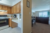 Located at 132 Tide Mill Ln in Hampton, Virginia, this two-story home offers a well-organized layout across two levels connected by a carpeted staircase with a classic railing. The main living area is bright and welcoming, featuring soft wall-to-wall carpeting and large sliding glass doors dressed with vertical blinds that invite generous natural light and provide views of the outdoors. Adjacent to the living room, the dining area is accented by an elegant chandelier and vaulted ceiling detail, creating a refined yet relaxed atmosphere for everyday meals and gatherings. The kitchen is equipped with warm oak cabinetry, a stainless steel sink, a dishwasher, and an electric range with oven, offering practical functionality in a compact, efficient layout with tile flooring. Multiple bedrooms are spread across the home, each featuring plush carpeting, ceiling fans, and windows that allow natural light to filter in. The bedrooms offer ample space and include walk-in closet access, providing generous storage. The bathroom features a full tub-shower combination with clean white tile surround, a vanity, and neutral finishes throughout. The overall ambiance of the home is warm and understated, with neutral tones and consistent finishes creating a cohesive and comfortable living environment throughout both floors.