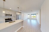 Located at 42 N Beacon Street in Boston's Allston neighborhood, this well-appointed 3-bedroom, 2-bathroom unit offers a thoughtfully designed floor plan across a single level. Light-toned hardwood flooring flows throughout, lending a clean, cohesive aesthetic to every room.

The open-concept kitchen and living area serves as the heart of the unit. The kitchen is outfitted with white shaker cabinetry, white subway tile backsplash, stainless steel appliances — including a refrigerator, range, and microwave — and a central island with a sink and pendant lighting above. The living area extends generously from the kitchen, bathed in natural light from large windows with views of the surrounding neighborhood.

The three bedrooms are bright and well-proportioned, each featuring large windows with urban and tree-lined views. Four closets are distributed throughout the unit, providing ample storage. The two bathrooms are finished with large-format tile flooring, warm wood vanities with white countertops, and white subway tile surrounds — one featuring a soaking tub and the other a glass-enclosed walk-in shower. Recessed lighting and brushed brass fixtures add polished, modern touches throughout the entire unit.