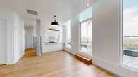 Located at 120 Place Charles-le Moyne in Longueuil, this well-appointed 2-bedroom, 2-bathroom residence offers a bright, modern living experience across a single thoughtfully designed floor. Light hardwood flooring flows throughout, complementing the clean white walls and contemporary finishes that define the space.

The open-concept kitchen and living area serves as the heart of the home, featuring sleek white cabinetry extending to the ceiling, a stainless steel appliance package, under-cabinet lighting, and a generous white quartz island with an integrated sink — all bathed in natural light from floor-to-ceiling windows.

The primary bedroom is generously proportioned, offering tall windows with sweeping city and river views, and direct access to a walk-in closet with built-in shelving. The second bedroom is equally bright, also benefiting from large windows framing the skyline. Both bathrooms are finished in crisp white tile, with one featuring a soaker tub and glass shower enclosure. Two closets and a dedicated in-unit laundry room with full-size Whirlpool washer and dryer add practical convenience.

The standout feature is the expansive private balcony with glass railings, offering unobstructed panoramic views of the St. Lawrence River and the Montreal skyline — an exceptional outdoor retreat above the city.