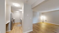 This single-story, 3-bedroom, 2-bathroom home offers a thoughtfully arranged layout that maximizes every square foot. The open living area greets you with light-toned wood-look flooring, neutral walls, and a textured ceiling, creating a bright and welcoming atmosphere. Natural light filters in through a window with blinds, enhancing the airy feel of the space. A hallway connects the main living area to the rest of the home, providing clear separation between living and sleeping quarters.

The galley-style kitchen is efficiently designed with gray shaker cabinets, white countertops, stainless steel appliances including a refrigerator and range, and a single-basin sink — all set atop matching wood-look flooring. The layout is practical and streamlined for everyday use.

Each of the three bedrooms features soft, neutral carpet and clean white walls, offering a comfortable and restful environment. The primary bedroom is a generous size and includes a sliding-door closet with built-in shelving for ample storage.

The two bathrooms are finished with wood-look flooring, white countertops, and vanities with ample cabinet space. One bathroom features a full tub-shower combination with a curved curtain rod, while the second offers a similarly clean and functional design. Together, the spaces present a cohesive, move-in-ready home with consistent, modern finishes throughout.