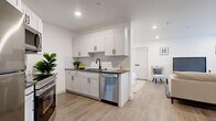 Located at 458 Parker Ave in Philadelphia, PA, this well-appointed 1-bedroom, 1-bathroom unit offers a thoughtfully designed open-concept layout on a single floor. Light wood-tone flooring flows seamlessly throughout, creating a cohesive and airy feel across all living areas.

The kitchen is a standout feature, showcasing white shaker-style cabinetry with matte black hardware, a classic white subway tile backsplash, dark countertops, and a full suite of stainless steel appliances including a refrigerator, oven, built-in microwave, and dishwasher. The kitchen opens directly into the living area, which benefits from a window overlooking greenery, recessed lighting, and ample room for both a seating arrangement and a dedicated workspace.

The bedroom is a calm, white-walled retreat with recessed lighting, soft natural tones, a plush area rug, and a double-door closet for convenient storage. The bathroom features gray tile flooring, a soaking tub/shower combination lined with striking large-format hexagonal white tiles, and matte black fixtures that add a modern, polished contrast. The overall design is clean, contemporary, and functional throughout.