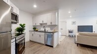 Located at 458 Parker Ave in Philadelphia, PA, this well-appointed 1-bedroom, 1-bathroom unit offers a thoughtfully designed open-concept layout on a single floor. Light wood-tone flooring flows seamlessly throughout, creating a cohesive and airy feel across all living areas.

The kitchen is a standout feature, showcasing white shaker-style cabinetry with matte black hardware, a classic white subway tile backsplash, dark countertops, and a full suite of stainless steel appliances including a refrigerator, oven, built-in microwave, and dishwasher. The kitchen opens directly into the living area, which benefits from a window overlooking greenery, recessed lighting, and ample room for both a seating arrangement and a dedicated workspace.

The bedroom is a calm, white-walled retreat with recessed lighting, soft natural tones, a plush area rug, and a double-door closet for convenient storage. The bathroom features gray tile flooring, a soaking tub/shower combination lined with striking large-format hexagonal white tiles, and matte black fixtures that add a modern, polished contrast. The overall design is clean, contemporary, and functional throughout.