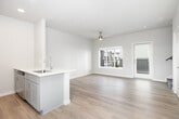 This well-designed two-story home offers 2 bedrooms and 3 bathrooms across two thoughtfully laid-out floors. The main level features an open-concept kitchen and living area finished with warm light hardwood flooring. The kitchen is equipped with stainless steel appliances, including a refrigerator, range, and microwave, complemented by gray shaker-style cabinetry, a built-in dishwasher, and a central island with a undermount sink and clean white countertops. Recessed lighting illuminates the space, while a ceiling fan adds comfort to the living area. A door leads out to a private balcony with metal railing, offering neighborhood views. The upper floor houses the bedrooms, each featuring plush carpet flooring and generous closet space. The primary bedroom is a comfortable size, bathed in natural light. The bathrooms are well-appointed, with one featuring a sleek sliding glass shower enclosure and another offering a full tub-shower combo with chrome fixtures. Hardwood-style flooring carries through the bathrooms. Neutral tones, crisp white walls, and consistent modern finishes create a cohesive, bright ambiance throughout the entire home.