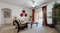 This single-floor residence offers a thoughtfully designed layout that balances comfort and functionality throughout. The open-concept living and dining area serves as the heart of the home, featuring plush carpeting, crown molding, a ceiling fan with light fixture, and an arched architectural detail that adds character to the space. A sliding glass door with bold red drapes opens to a private balcony, allowing natural light to fill the room. The dining area transitions seamlessly from the kitchen via wood-look flooring, creating a natural distinction between spaces.

The kitchen is well-equipped with light maple cabinetry, white countertops, and a full suite of stainless steel appliances including a refrigerator, range, microwave, and dishwasher. Wood-look flooring ties the kitchen together with clean, practical appeal.

The residence features multiple bedrooms, each carpeted and filled with natural light from large windows dressed with decorative valances and curtains. Each bedroom offers ample space and closet access, providing comfortable private retreats.

Two full bathrooms are finished with white tile surrounds, soaking tubs, white vanity cabinetry, and warm wood-look flooring, offering a clean and functional aesthetic throughout. The consistent warm-toned color palette unifies the entire residence.