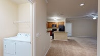 Located at 1141 Kendall Town Blvd in Jacksonville, FL, this single-floor, 2-bedroom, 3-bathroom home offers a well-designed layout with a comfortable, functional feel throughout. The open-concept kitchen is a standout feature, boasting warm honey-toned wood cabinetry, granite countertops, a center island, and black appliances including a range, built-in microwave, and refrigerator with ice maker. Tile flooring anchors the kitchen, which flows seamlessly into two distinct living areas carpeted in a neutral, warm tone — ideal for both relaxing and entertaining. A dedicated laundry room houses a full-size washer and dryer and is conveniently accessible from the main corridor. The two bedrooms are generously sized, each featuring plush carpet, ceiling fans, and large windows that bring in ample natural light and outdoor views. The primary bedroom includes an en-suite bathroom with a double-sink granite vanity, rich wood cabinetry, a glass-enclosed walk-in shower, and an adjacent walk-in closet with built-in shelving. Crown molding, textured ceilings, and a cohesive neutral color palette contribute to the polished, move-in-ready ambiance of this well-appointed Jacksonville home.