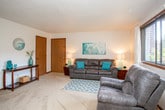 This single-floor unit offers a well-organized layout that connects living, dining, kitchen, and sleeping areas in a practical and comfortable arrangement. The living room is generously sized, featuring carpet flooring, a textured ceiling, and a window that brings in natural light while providing outdoor views. A console table near the entryway adds a welcoming touch, and warm-toned doors contribute to a cohesive interior aesthetic.

The kitchen is equipped with dark wood cabinetry, granite-style countertops, a double basin sink, and white appliances including a refrigerator, dishwasher, and range. The tile flooring provides easy maintenance in this functional cooking space. Adjacent to the kitchen, the dining area accommodates a bistro-height table set beneath a window with garden views, creating an inviting spot for meals.

Two bedrooms offer carpeted floors, textured ceilings, and windows with outdoor views. One bedroom includes a sliding-door closet with a hanging rod. The full bathroom features warm wood cabinetry, a single-sink vanity, a mirrored medicine cabinet, and a shower-tub combination, providing all essential amenities in a compact and efficient layout.