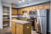 This single-story Memphis residence offers three bedrooms and two bathrooms across a thoughtfully designed floor plan. The interior features wood-style flooring throughout the main living areas, complemented by neutral wall tones that create a bright, cohesive atmosphere.

The kitchen serves as a functional centerpiece, equipped with stainless steel appliances including a refrigerator, electric range, microwave, and dishwasher. Warm-toned wood cabinetry extends to the ceiling, providing ample storage, while a center island with a laminate countertop adds prep space. Track lighting illuminates the area effectively.

The living room includes crown molding, a ceiling fan, and a glass door that invites natural light. An adjacent dining area features hardwood-style flooring, crown molding, and a pendant light fixture. A graceful arched passageway connects the hallway to additional living spaces, adding architectural character.

The bedrooms are carpeted and include ceiling fans and windows with natural light. One bathroom features a double-sink vanity with warm wood cabinetry and a large mirror, while the second includes a tub-shower combination with classic white tile accented by a bold navy border. A dedicated laundry room houses a full-size washer and dryer with built-in shelving above.