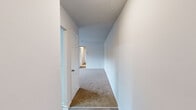 This single-floor residence features a thoughtfully arranged layout with two bedrooms, two bathrooms, a kitchen, a dedicated closet, and three connecting hallways. The kitchen is equipped with gray shaker-style cabinetry, granite-look countertops, wood-look tile flooring, and black appliances including a refrigerator, electric range, dishwasher, and an overhead range hood, with a skylight adding a touch of natural brightness. The open pass-through connects the kitchen to the adjacent living area, enhancing the sense of flow between spaces. Both bedrooms feature neutral carpet flooring and windows that allow natural light to filter in. The spacious primary bedroom includes access to a walk-in closet outfitted with dual hanging rods, providing ample storage. The two bathrooms are finished consistently, each featuring gray cabinetry with granite-look countertops and wood-look tile flooring. One bathroom offers a glass-enclosed stand-up shower, while the other includes a full tub-shower combo with white tile surround. Hallways connect the main living areas to the private quarters, featuring carpet flooring and clean white walls throughout. The overall aesthetic is clean, neutral, and move-in ready.