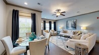 Located at 1000 Knights Spur Ct in Simpsonville, SC, this 2-bedroom, 2-bathroom residence offers a thoughtfully designed single-floor layout that maximizes both comfort and functionality. The open-concept living and dining area serves as the heart of the home, featuring rich dark hardwood flooring, crown molding with a two-tone color scheme of soft blue and warm neutral walls, and abundant natural light streaming through multiple windows dressed with elegant navy drape panels. A ceiling fan anchors the living space, which flows seamlessly into a well-appointed kitchen boasting rich wood cabinetry, granite countertops, stainless steel appliances, and a breakfast bar with modern pendant lighting — ideal for casual dining or entertaining. The primary bedroom is generously sized with plush carpeting, natural light, and access to a dedicated closet. The second bedroom mirrors this comfort with carpet flooring and its own closet space. Five closets total provide exceptional storage throughout the residence. Both bathrooms are clean and functional, with one featuring a full tub-shower combination. A dedicated laundry room with washer and dryer hookups adds everyday convenience. The overall ambiance is modern yet inviting, with consistent finishes that lend a cohesive, polished feel throughout.