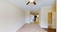 Located at 3304 Green Valley Dr in Fayetteville, North Carolina, this two-story home offers a comfortable and well-appointed layout designed for everyday living. The interior is finished with a warm, neutral color palette throughout, creating a welcoming and cohesive atmosphere from room to room.

The main living area features plush wall-to-wall carpeting, elegant crown molding, and a ceiling fan with a light fixture — details that add both comfort and character to the space. The open sightlines from the living area draw the eye toward the rear of the home, where a door provides access to the outdoors, allowing for natural light to filter through.

Transitioning deeper into the home, the layout flows naturally into the kitchen area, which is distinguished by tile flooring and a raised bar or counter feature. Dark appliances provide a subtle contrast against the lighter surroundings. The open connection between the living and kitchen spaces supports a functional and social floor plan.

Crown molding and clean white baseboards are consistent throughout, reinforcing the home's attention to finish detail. Spanning two floors, the property offers generous living space with room for a variety of uses. Overall, the home presents a tidy, move-in ready aesthetic with classic design elements suited to a range of lifestyles.