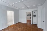 Located at 726 N Alfred St in the heart of West Hollywood, this single-floor residence offers a well-organized layout with a clean, neutral aesthetic throughout. The living areas are anchored by warm hardwood flooring and distinctive coffered ceilings with a beadboard finish, lending a subtle architectural character to the space. Natural light filters in through windows dressed with vertical blinds, contributing to a bright and open atmosphere.

The galley-style kitchen is efficiently designed, featuring white cabinetry with modern hardware, classic white subway tile backsplash, light stone countertops, a double stainless steel sink with a brass faucet, a gas range, and a full-size refrigerator. White tile flooring and a window with decorative ironwork complete the kitchen's clean, functional look.

The bedrooms are generously proportioned, each offering hardwood floors, the signature coffered ceilings, and abundant closet space — including rooms with dual open closets. Wall-mounted air conditioning units provide climate control. The bathroom is well-appointed with a tub and shower combination enclosed by sliding glass doors, warm wood cabinetry for storage, and classic white fixtures. The overall ambiance of the space is bright, practical, and move-in ready.