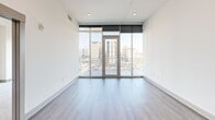 Located on the 8th floor in the heart of Charlotte's Brooklyn Village, this modern 2-bedroom, 2-bathroom residence offers a thoughtfully designed open layout with striking downtown skyline views. The living area features wide-plank hardwood flooring, floor-to-ceiling windows, and a glass balcony door that floods the space with natural light while framing panoramic city views. Built-in shelving adds a functional yet stylish touch to the living room.

The kitchen is a standout, showcasing sleek white cabinetry, a gray tile backsplash, stainless steel appliances, and a generous island with a marble-veined quartz countertop and double undermount sink, accented by modern pendant lighting. The open layout connects the kitchen seamlessly to the living and dining areas.

The spacious primary bedroom features plush carpeting, floor-to-ceiling windows with city views, and direct balcony access. Its en-suite bathroom is elegantly appointed with large-format tile flooring, a black granite double vanity, a soaking tub with gray tile surround, and a separate glass-enclosed shower. A walk-in closet with dual hanging rods and shelving provides ample storage. The second bedroom also enjoys abundant natural light and city views, served by a well-appointed second bathroom.