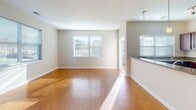 This single-floor residence offers a thoughtfully designed layout with a blend of functional and aesthetic details throughout. The open living area is a standout feature, showcasing warm hardwood flooring that extends throughout the main living spaces and reflects ample natural light from multiple windows. A teal accent wall and track lighting add a distinctive touch to one of the living areas, while a pendant light fixture marks the transition to the kitchen via a breakfast bar with dark granite countertops.

The kitchen is equipped with rich, dark-stained cabinetry, granite countertops, and a full suite of stainless steel appliances, including an electric range with smooth cooktop and an over-the-range microwave. A window above the counter brings in natural light.

The bedrooms are carpeted for comfort, each featuring neutral tones and windows with blinds that provide outdoor views and natural illumination. One bedroom includes access to a generously sized walk-in closet fitted with dual hanging rods and shelving on multiple levels.

Both bathrooms are finished with tile flooring, dark wood vanities topped with granite, and full tub-shower combinations with chrome fixtures, offering a consistent and polished aesthetic throughout the home.