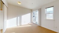 This single-floor studio unit offers a clean, functional layout designed to maximize efficiency and comfort. The open-plan living space is finished with neutral wall-to-wall carpeting that runs throughout, contributing to a warm and cohesive feel. Large sliding glass doors lead to a private balcony, allowing generous natural light to fill the interior and creating a seamless connection to the outdoors. An additional window further enhances the brightness of the space.

The kitchenette is thoughtfully arranged along one wall, featuring light maple cabinetry—both upper and lower—with ample storage. A deep countertop with a wood-trimmed edge provides practical workspace, complemented by a compact stainless steel refrigerator and microwave, making day-to-day living convenient. An open shelf above adds both storage and visual interest.

A dedicated closet with a hanging rod provides organized storage within the main living area. The bathroom is efficiently designed with tile flooring, a vanity featuring a light maple cabinet and warm countertop, a mirrored medicine cabinet above, and a full bathtub. Clean white walls and crisp trim throughout the unit maintain a bright, minimal aesthetic that makes the space feel open and easy to personalize.