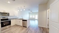 This thoughtfully designed 1-bedroom, 1-bathroom residence offers an efficient and functional single-floor layout that maximizes every square foot. The open-concept living area seamlessly connects the kitchen, dining, and living spaces, creating a bright and airy atmosphere enhanced by natural light streaming through large windows and a ceiling fan overhead.

The kitchen is a standout feature, boasting crisp white shaker cabinetry, granite countertops, a tile backsplash, and a full suite of stainless steel appliances including a refrigerator, range, microwave, and dishwasher. Stylish pendant lighting illuminates the peninsula, which provides additional counter space and casual seating potential. Wood-look flooring runs throughout the main living areas, contributing to a clean, contemporary aesthetic.

The living room opens to a private balcony, extending the usable space outdoors. The spacious bedroom features plush carpeting, a ceiling fan, and a window with outdoor views. Adjacent to the bedroom is a well-sized bathroom with granite vanity countertops and a tub-shower combination. A generous walk-in closet with multi-tier wire shelving provides ample storage. The unit is completed by a dedicated laundry area, adding everyday convenience to this move-in-ready residence.