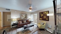 This single-floor residence offers a thoughtfully designed layout that maximizes both function and comfort. The living room serves as the heart of the space, featuring wood-look flooring, a ceiling fan, and a textured ceiling. Warm neutral wall tones complement the room's décor, while a sliding glass door floods the area with natural light and provides access to an outdoor balcony. The open-concept design connects the living room to a dedicated dining area and a peninsula-style breakfast bar, creating a seamless flow ideal for entertaining.

The galley kitchen is equipped with dark espresso cabinetry, granite-style countertops, a full suite of black appliances including a refrigerator and electric range, and a stainless steel sink. A small window provides additional natural light, and the layout offers generous counter and storage space.

The bedroom is generously sized with plush carpeting, multiple windows that invite natural light and outdoor views, and ample room for furnishings. A second, more intimate bedroom configuration is also visible, offering versatility.

The bathroom features a tub-shower combination, wood-look flooring, and a built-in shelving closet conveniently positioned at the entry, providing practical storage within easy reach.