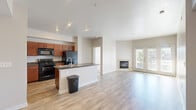 Located at 325 E Fifth St in Loveland, Colorado, this single-floor residence offers a well-designed open-concept layout that seamlessly connects the kitchen, dining, and living areas. Light-toned wood-style flooring flows throughout the main living spaces, creating a clean and cohesive aesthetic.

The kitchen is a functional centerpiece, featuring rich cherry-toned cabinetry, dark granite-style countertops, a full suite of black appliances, and a peninsula island with a built-in sink — ideal for both meal preparation and casual dining. Recessed lighting illuminates the space efficiently.

The living area is bright and open, anchored by a tile-surround fireplace and framed by French doors that provide direct access to an outdoor patio, allowing natural light to pour in. The neutral wall tones and clean lines give the space a modern, understated character.

The bedroom is generously proportioned, finished with plush carpet and a large window that brings in additional natural light. It connects directly to a private bathroom, which includes a cherry-toned vanity with light stone-style countertops, a tub-shower combination with white tile surround, and wood-style flooring.

Additional highlights include a dedicated closet space off the bedroom and a separate entry door, contributing to a practical and comfortable everyday living environment.