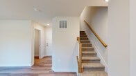 This three-story home offers a well-organized layout across three distinct levels, providing functional separation between living, sleeping, and entry spaces. The ground floor serves as the entry level, featuring hardwood-style flooring, recessed lighting, and staircase access to the upper floors. A closet on this level offers convenient storage near the entrance.

The main living level occupies the largest portion of the home and centers around an open-concept kitchen and living area. The kitchen is equipped with white shaker cabinetry, granite countertops, a large island with a built-in sink, stainless steel appliances including a refrigerator, range, and microwave, and pendant lighting overhead. A door from this level opens to a private balcony with outdoor views of surrounding greenery, allowing natural light to fill the space through multiple windows.

The upper floor houses all three bedrooms and two full bathrooms. The primary bedroom receives ample natural light through dual windows and features carpet flooring. The secondary bedrooms are similarly carpeted with window access. One bathroom includes a tub-shower combination with white tile surround and granite vanity, while the second features a glass-enclosed walk-in shower with matching finishes throughout.