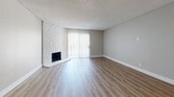 Located in Santa Ana, CA, this single-story 2-bedroom, 2-bathroom residence offers a well-organized layout with a comfortable and functional design throughout. The open living room is a standout space, featuring a striking white brick fireplace, wood-style flooring, a textured ceiling, and a sliding glass door that lets in abundant natural light. The kitchen is thoughtfully appointed with dark cabinetry, granite-style countertops, a mosaic tile backsplash, stainless steel appliances including a refrigerator, range, microwave, and dishwasher, and a peninsula that offers additional workspace and seating potential. Both bedrooms are generously sized with warm wood-style flooring, large windows fitted with vertical blinds, textured ceilings, and sliding mirrored or panel closets providing ample storage. The primary bedroom is notably spacious and connects to its own bathroom. The two bathrooms are clean and practical — one features a tub/shower combo with a curved curtain rod and granite-topped vanity, while the other includes a walk-in style shower. Wood-style flooring runs consistently throughout the unit, giving the space a cohesive and modern feel. A hallway connects all rooms efficiently, completing this well-designed residence.