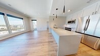 This 950-square-foot, 3-bedroom, 2-bathroom condominium at 855 N. Broadway, Unit 1417 in Denver, CO offers a well-appointed single-floor layout with modern finishes throughout. The open-concept kitchen and living area serves as the heart of the home, featuring a large center island with a quartz countertop and undermount sink, sleek white shaker cabinetry, stainless steel appliances including a refrigerator, range, and microwave, and a classic marble-style tile backsplash. Three pendant lights hang above the island, adding a contemporary touch. Light hardwood flooring flows throughout the main living areas and all three bedrooms, creating a warm, cohesive aesthetic. A stacked in-unit washer and dryer is conveniently located off the main living space. The primary bedroom spans 150 square feet and features a tray ceiling, a private en-suite bathroom with a dual-sink vanity, quartz countertops, and a marble-tiled walk-in shower, as well as direct access to a private balcony with outdoor views. Additional bedrooms include closets with built-in shelving and natural light from large windows. Two closets provide ample storage, and black hardware accents are consistent throughout, tying together the modern design.