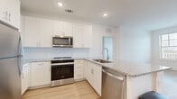 Located at 8402 IBM Drive in Charlotte, NC, this single-story home offers three bedrooms and two bathrooms within a thoughtfully designed floor plan. The interior features a clean, modern aesthetic defined by white walls, light wood-look flooring in the main living areas, and consistent use of white shaker-style cabinetry and granite countertops throughout.

The kitchen is a standout feature, equipped with stainless steel appliances including a refrigerator, range, microwave, and dishwasher. White shaker cabinets extend to the ceiling, providing ample storage, while the granite-topped island with an integrated sink adds both workspace and visual appeal. The kitchen flows naturally into the living area, which is bright and open with light wood flooring.

The primary bedroom is generously sized, carpeted for comfort, and includes a ceiling fan and windows that bring in natural light. The additional bedrooms are also carpeted and feature windows with exterior views. The primary bathroom offers a wide double-vanity with granite countertops and wood-look flooring. The second bathroom includes a full tub-shower combination, granite vanity, and matching finishes, maintaining a cohesive, contemporary style throughout the home.