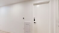 Located at 1704 N 17th St in Tampa, FL, this thoughtfully designed single-floor unit offers a cohesive modern aesthetic throughout its well-utilized interior. The space features light hardwood flooring that flows seamlessly through the main living areas, complemented by crisp white walls and a neutral color palette that creates a clean, airy atmosphere.

The galley-style kitchen is outfitted with flat-front gray cabinetry, stainless steel appliances including an electric range and microwave, a white countertop, and a undermount sink — a functional and stylish space for everyday living. Adjacent living areas benefit from large floor-to-ceiling windows that invite abundant natural light and frame views of the surrounding Tampa neighborhood, including lush palm trees and neighboring brick buildings.

The bedrooms feature soft blue-gray accent walls, warm hardwood floors, and upholstered platform beds. One bedroom includes an integrated wall unit with built-in cabinetry, a dedicated workspace, and a mounted TV — maximizing both storage and functionality. A keypad entry with a smart access panel is found at the unit's entrance, alongside a utility panel for added convenience.

Multiple bathrooms feature large-format cream tile flooring, frameless glass-enclosed showers with matte black fixtures, and floating vanities, delivering a spa-like, minimalist finish throughout.