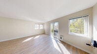 Located at 8500 20th Ave NE in Seattle's Wedgwood neighborhood, this one-bedroom, one-bathroom unit offers an efficiently designed single-floor layout. The main living area is the heart of the unit, featuring light wood-tone laminate flooring, neutral beige walls, and crisp white ceilings that together create a bright and airy atmosphere. Multiple windows flood the space with abundant natural light, while a sliding glass door opens directly onto a private balcony with views of surrounding greenery — a standout feature that brings the outdoors in. A wall-mounted heater provides in-unit climate control. The compact kitchenette is thoughtfully outfitted with dark cabinetry, a built-in microwave, a compact refrigerator, and a single-basin sink, offering essential cooking and storage functionality. The bathroom presents a clean, utilitarian design with a walk-in shower stall, a wall-mounted sink with a modern faucet, a mirrored medicine cabinet, and a towel ring — all finished in a bright white palette with light-toned flooring. The bedroom is generously proportioned relative to the overall footprint, making efficient use of the available space. This unit is well-suited for those seeking a manageable, low-maintenance living space in a residential Seattle neighborhood.