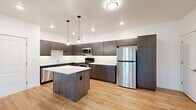 Located in Tumwater, WA, this well-designed one-bedroom, one-bathroom unit offers a thoughtful layout across a single floor. The standout feature is the expansive, modern kitchen, which boasts rich dark cabinetry, a classic subway tile backsplash, quartz countertops, a center island with pendant lighting, and a full suite of stainless steel appliances including a refrigerator, range, microwave, and dishwasher. The kitchen flows seamlessly into the open living area, which is bathed in natural light and finished with warm hardwood-style flooring that extends throughout the unit.

The living space is bright and airy, enhanced by clean white walls and a ceiling fan, creating a comfortable and inviting atmosphere. A sliding glass door leads to an outdoor area, offering views of the surrounding greenery. The bedroom is a well-proportioned retreat featuring a ceiling fan, multiple windows that bring in natural light, and continued hardwood-style flooring. The bathroom is clean and functional, complete with a full soaking tub and tub surround. The overall design aesthetic is clean and contemporary, with modern finishes that create a cohesive and stylish living environment.
