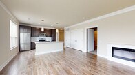 Located at 3600 Park East Dr in Beachwood, OH, this single-floor residence offers six bedrooms and two bathrooms across a generously sized layout. The open-concept kitchen and living area serves as the heart of the home, featuring rich dark-brown cabinetry, stainless steel appliances including an electric range and over-the-range microwave, a white subway tile backsplash, and light quartz countertops. A central island provides additional prep and gathering space. Light wood-tone flooring flows throughout the main living areas, complementing the neutral, warm wall tones and clean white trim throughout. The living room is highlighted by a sleek, modern linear fireplace set against a crisp white surround, adding both warmth and visual appeal. The bedrooms are carpeted for comfort, with the primary bedroom offering a well-proportioned layout and access to a spacious walk-in closet featuring built-in shelving and hanging rods. A second closet with wire shelving provides additional storage. Both bathrooms are finished with large-format tile flooring, dark vanity cabinetry with brushed hardware, stone-look countertops, and a full tub-shower combination. Hallways connect the rooms efficiently, and recessed lighting throughout ensures a bright, polished ambiance across the entire residence.