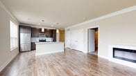 Located at 3600 Park East Dr in Beachwood, OH, this single-floor residence offers six bedrooms and two bathrooms across a generously sized layout. The open-concept kitchen and living area serves as the heart of the home, featuring rich dark-brown cabinetry, stainless steel appliances including an electric range and over-the-range microwave, a white subway tile backsplash, and light quartz countertops. A central island provides additional prep and gathering space. Light wood-tone flooring flows throughout the main living areas, complementing the neutral, warm wall tones and clean white trim throughout. The living room is highlighted by a sleek, modern linear fireplace set against a crisp white surround, adding both warmth and visual appeal. The bedrooms are carpeted for comfort, with the primary bedroom offering a well-proportioned layout and access to a spacious walk-in closet featuring built-in shelving and hanging rods. A second closet with wire shelving provides additional storage. Both bathrooms are finished with large-format tile flooring, dark vanity cabinetry with brushed hardware, stone-look countertops, and a full tub-shower combination. Hallways connect the rooms efficiently, and recessed lighting throughout ensures a bright, polished ambiance across the entire residence.
