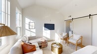 Located at 934 E Gay St in Columbus, Ohio, this single-floor unit showcases a carefully curated blend of modern and warm design elements. The open-concept layout connects the kitchen, living, and sleeping areas seamlessly, creating a cohesive and functional living space.

The kitchen is a standout feature, outfitted with sage green shaker-style lower cabinets, crisp white upper cabinets, warm butcher block countertops, and a striking matte black sink and faucet. A classic white square tile backsplash lines the walls, complemented by open wood shelving and recessed lighting. Light hardwood flooring runs throughout, adding warmth and continuity.

The living area is defined by dramatic vaulted ceilings that amplify the sense of openness and allow natural light to flood the space through large windows. A sliding black barn door adds an architectural focal point and provides access to additional utility space.

The sleeping area flows naturally from the living space, benefiting from the same soaring ceilings and natural light. A large window frames outdoor views, while the light-toned palette and hardwood floors maintain a calm, airy atmosphere throughout.

The bathroom features a warm wood vanity, white countertop, matte black fixtures, a large mirror, and a tiled shower, with a bold olive green accent wall adding a distinctive design touch. This unit offers a well-appointed, modern living experience in the heart of Columbus.